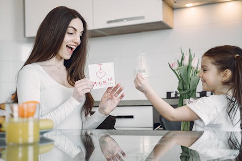 Photo of Child Showing Finger Heart Sign to Her Mom