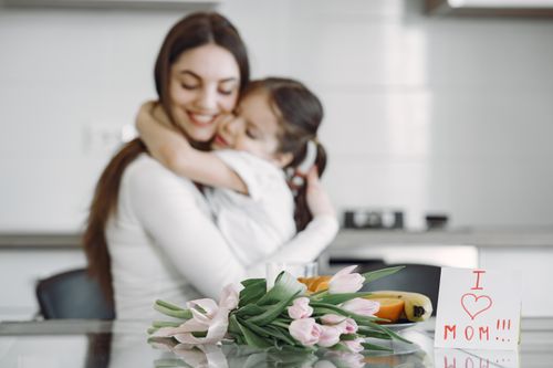 Free A heartwarming moment between mother and child with tulips and love note. Stock Photo