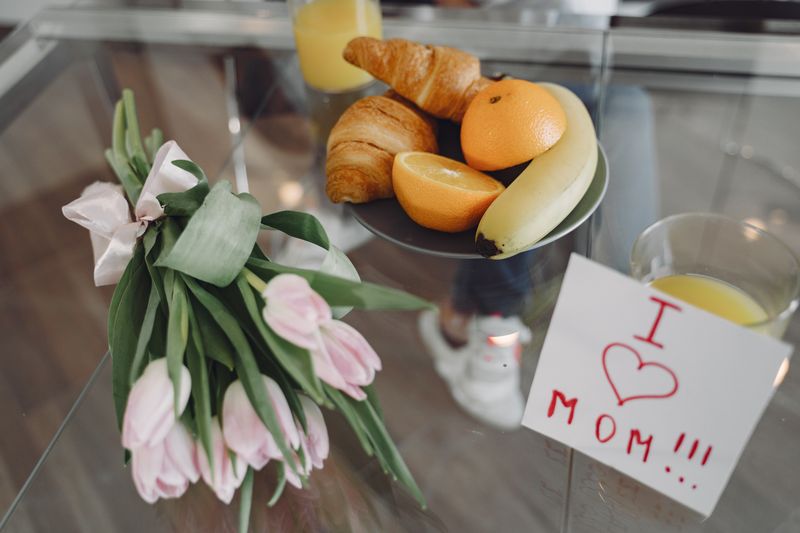 Pink tulips with a love letter on a glass table, perfect for Mother's Day