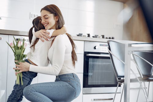 Free Photo of Woman Hugging Her Child While Holding Tulips Stock Photo