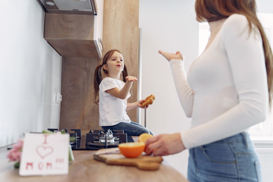 Mother and daughter sharing a fun moment in a modern kitchen with breakfast.