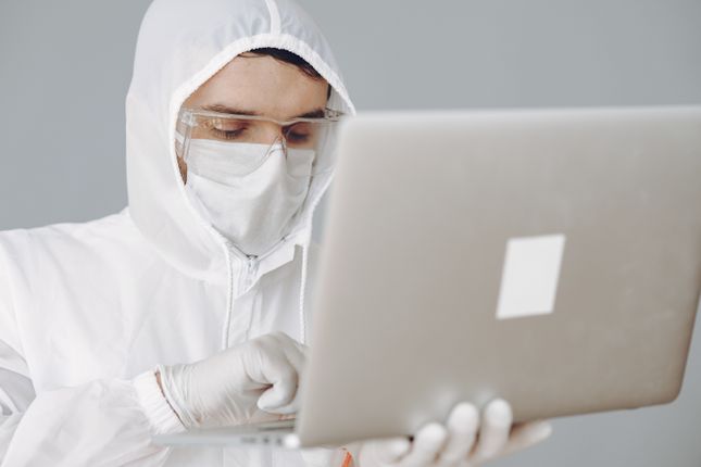 Person in personal protective equipment using a laptop to complete WHMIS online certification training in Canada