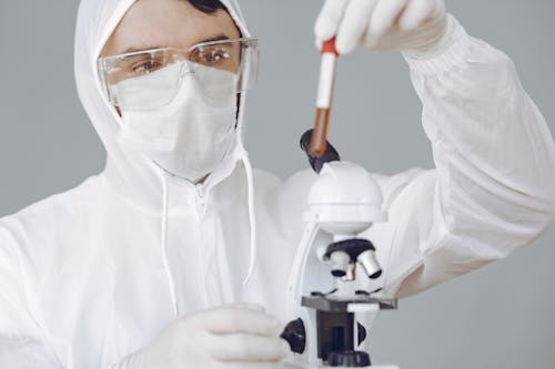 Free Person Using Microscope While Holding Test Tube Stock Photo