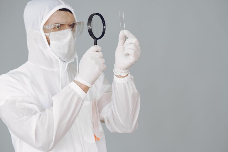 Photo Of Person Using Magnifying Glass While Holding A Glass Slide