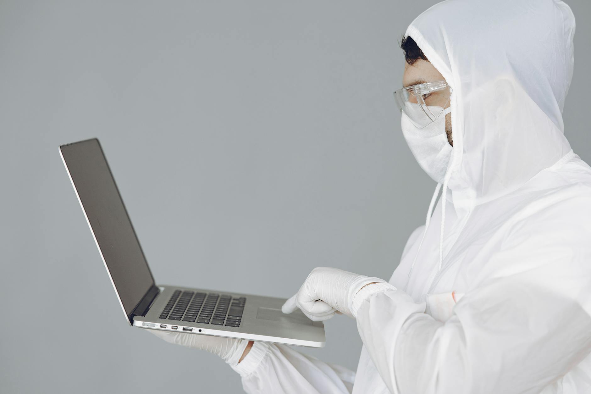 Photo of Person in Personal Protective Equipment Using MacBook