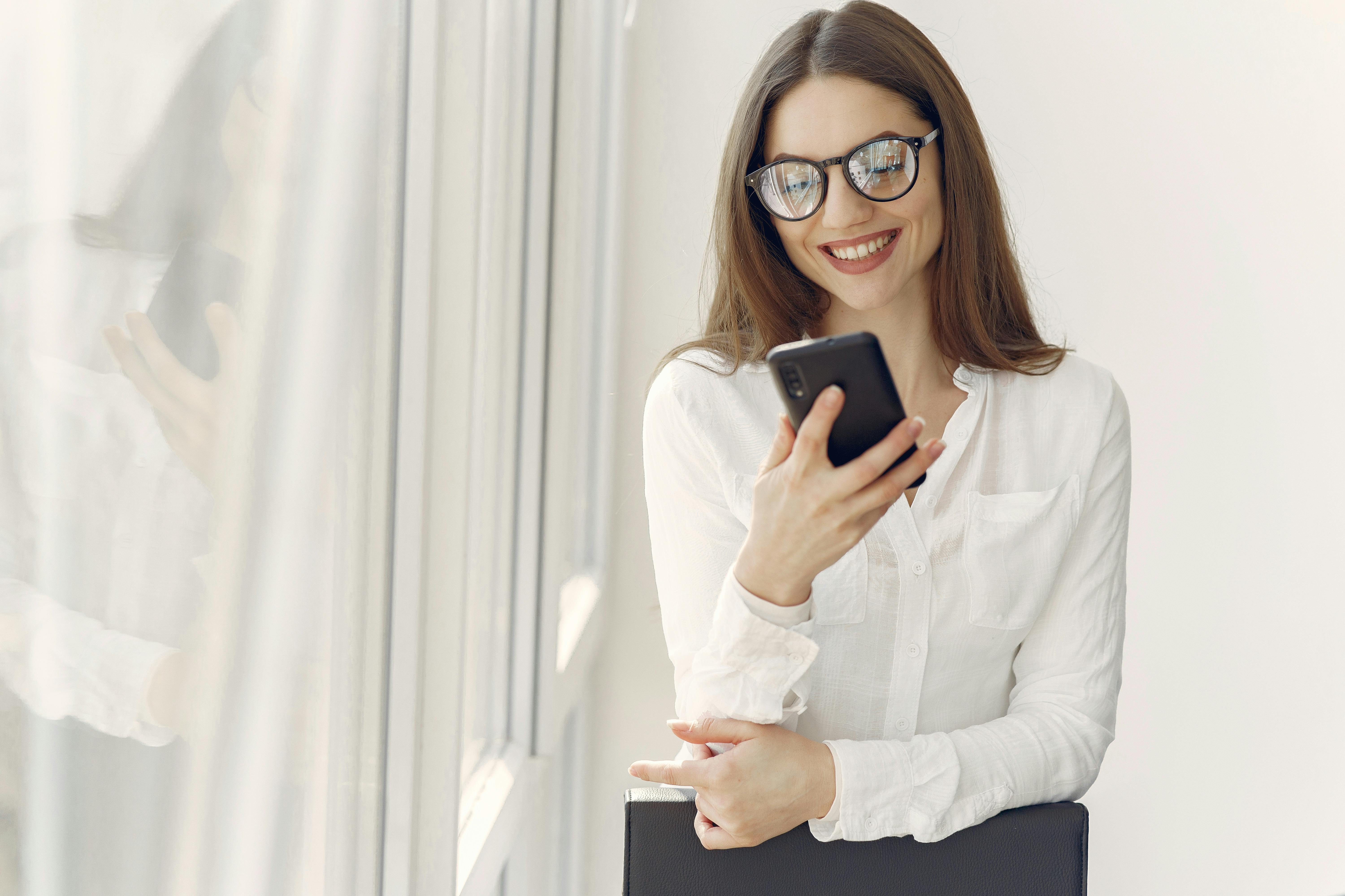 smiling woman using smartphone in office