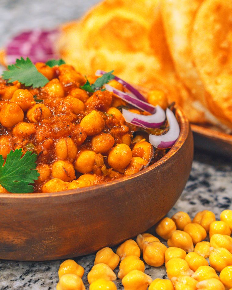 A bowl of spiced chickpeas topped with onion, served with bread