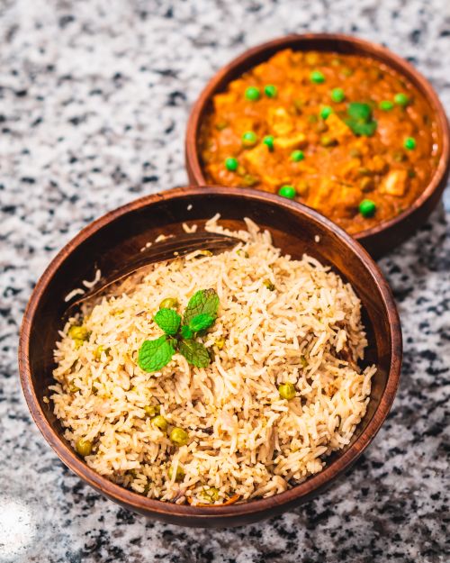 Free From above bowl with delicious boiled rice with green peas served with bowl of meat stew in tomato sauce on marble table Stock Photo