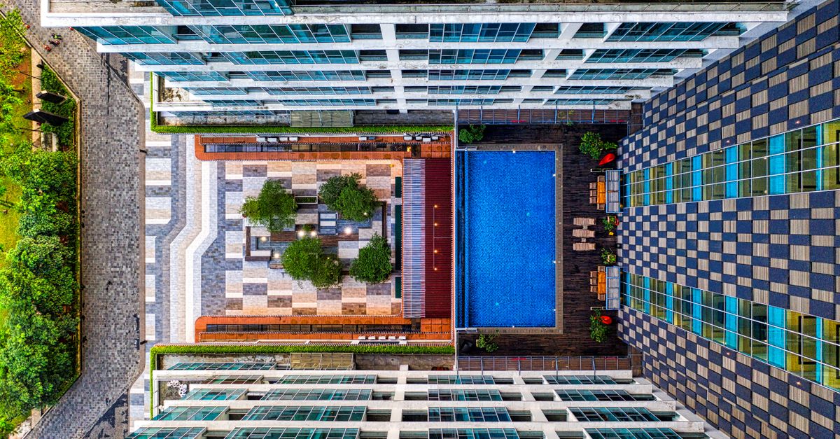 High-angle drone shot of a modern apartment complex with a swimming pool in South Tangerang, Indonesia.