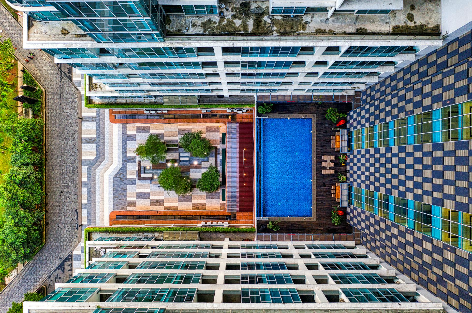 High-angle drone shot of a modern apartment complex with a swimming pool in South Tangerang, Indonesia.