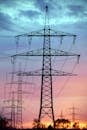 在壮观的日落天空映衬下，电力塔展示着高压传输的景象