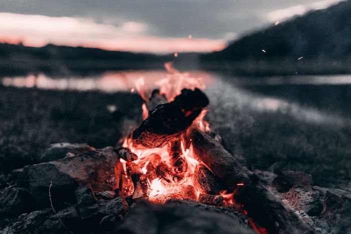 Bonfire near a lake with mountains at night