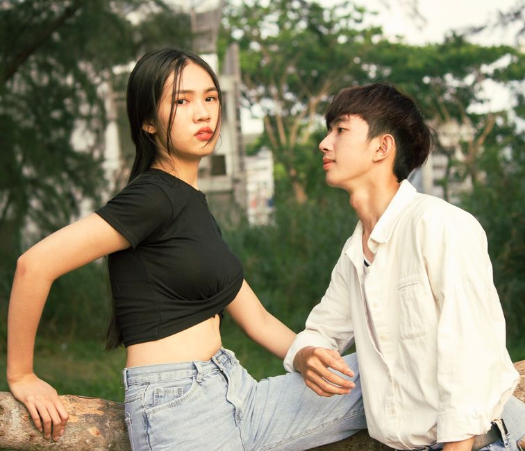 A young couple in a casual setting, enjoying each other's company outdoors in a green park.