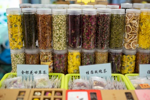 High angle of glass jars filled with assorted spices and dry fruits placed on stall in traditional Asian food market