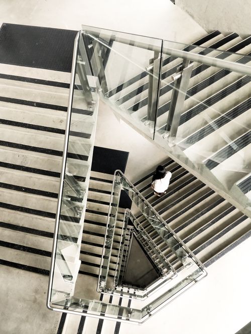 Free Artistic top view of a modern geometric staircase with glass panels and metal railings. Stock Photo