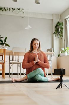 一名女子在光线充足的舒适室内，于瑜伽垫上冥想