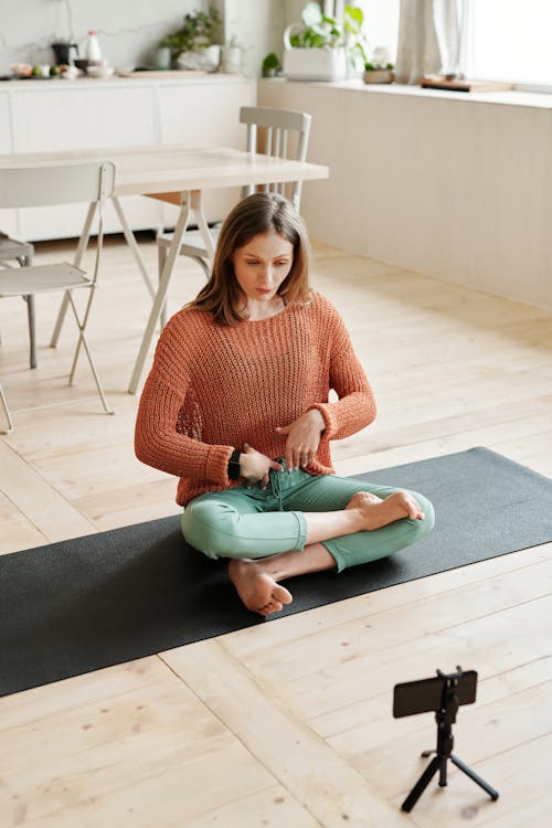 Woman in Orange Sweater Sitting on Black Yoga Mat