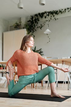 Woman practicing yoga indoors, demonstrating a stretching pose with natural lighting.