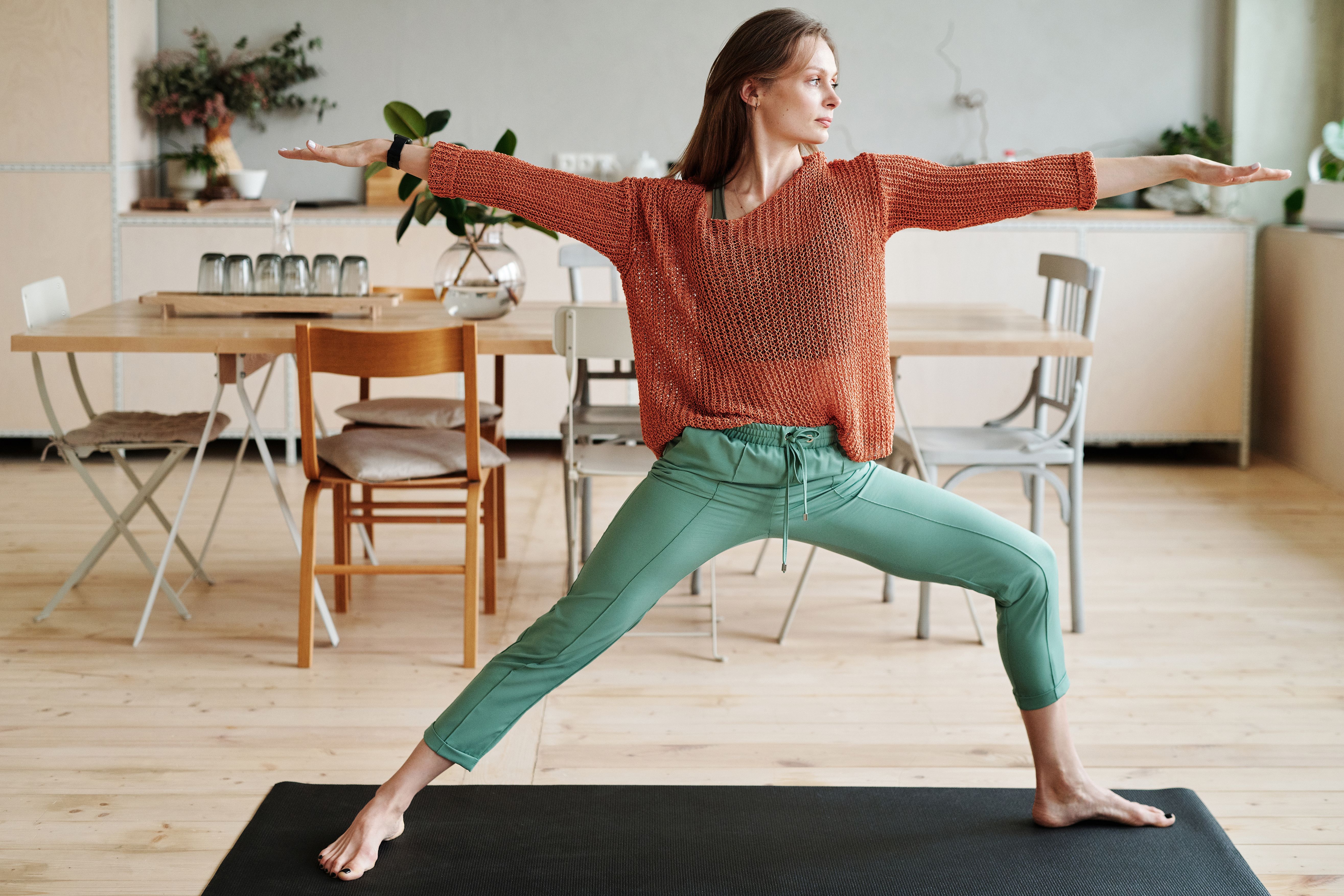 Woman in yoga pose on mat in a stylish home, emphasizing flexibility and balance.