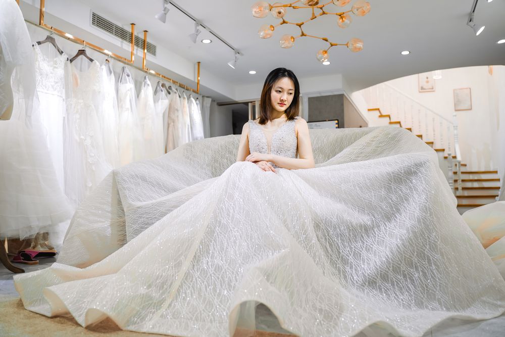 เจ้าสาวชาวเอเชียในชุดแต่งงานสีขาวนั่งในร้านชุดเจ้าสาว