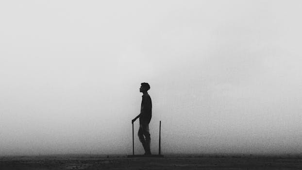 在混凝土墙附近的干燥地形上，一个无法辨认的男性轮廓以一条腿靠着木棍站立，呈现为黑白侧面图