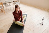 一名年轻女子在室内练习瑜伽，她用智能手机设置录音，以展示其灵活性和正念