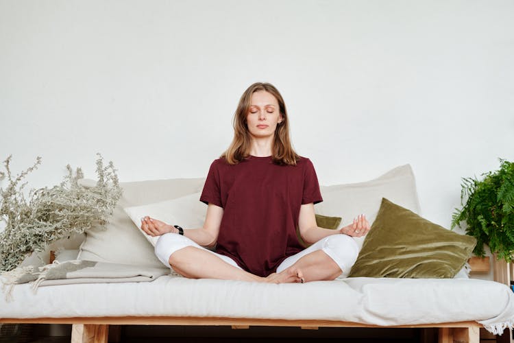 Woman In Red Shirt Sitting On Couch Meditating