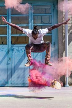Skateboarder jumps in vibrant pink powder cloud capturing urban street art vibe.