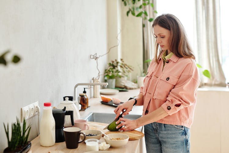 Woman In Pink Jacket Slicing Avocado