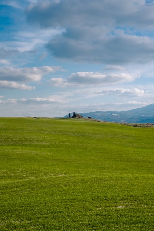 Free Vast green fields under a blue sky in the picturesque Tuscan countryside. Stock Photo