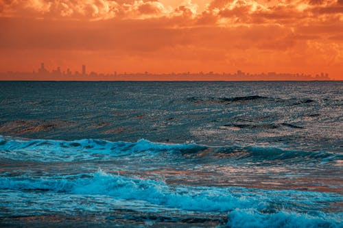 Free Ocean Waves Under Orange Sky during Sunset Stock Photo