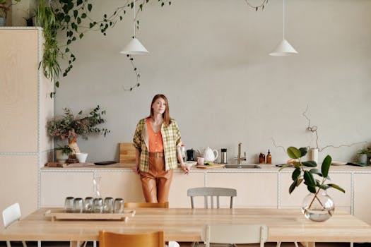 Modern kitchen with a stylish woman leaning on the counter, surrounded by plants.