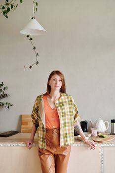 一位女士站在时尚厨房里，厨房装饰现代，并融入了自然元素