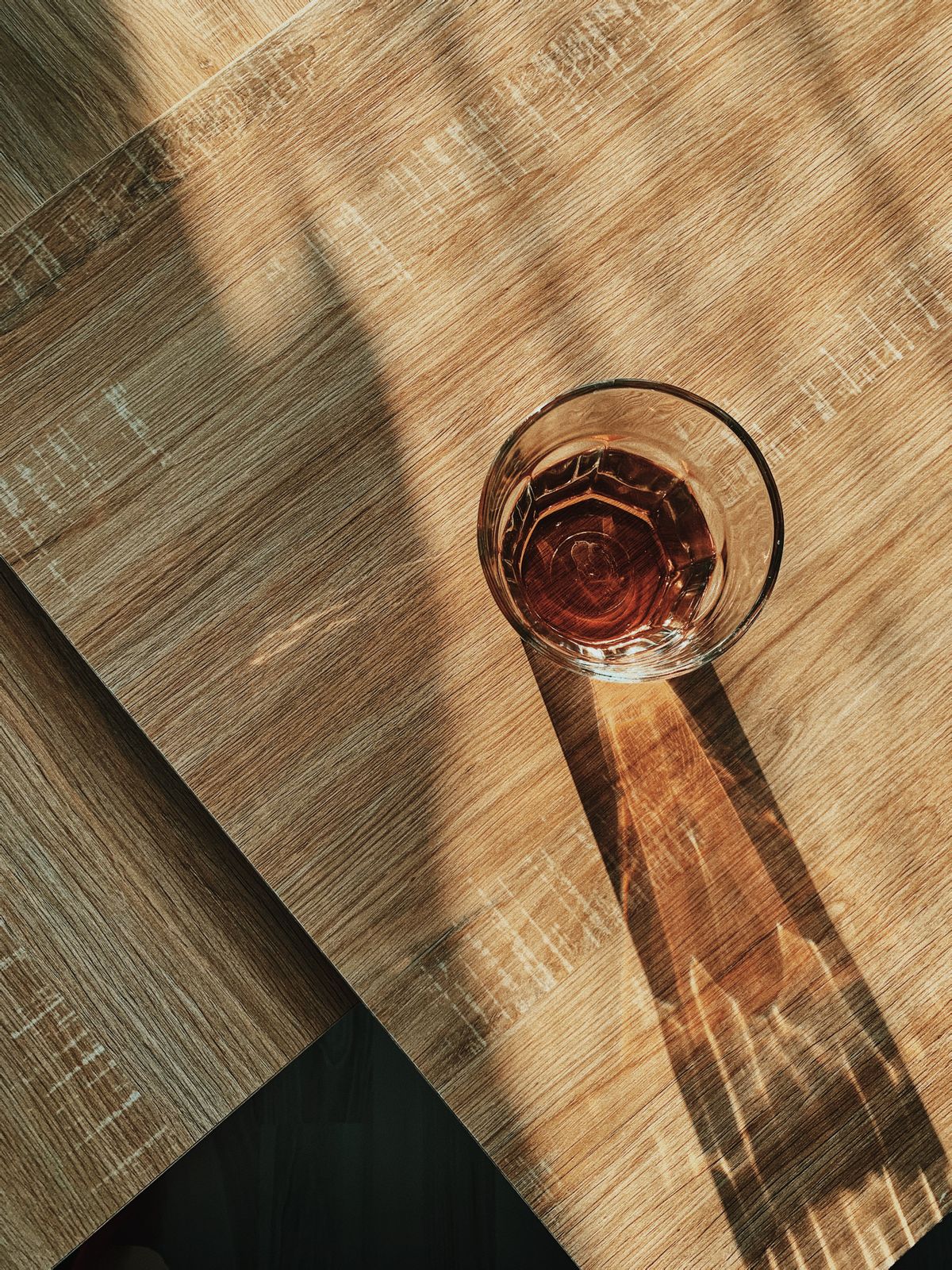 Ein Glas Wasser steht in der Sonne auf einem Holztisch