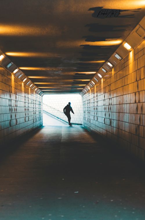 Free A silhouette of a skateboarder gliding through a brightly lit tunnel, capturing a dynamic urban moment. Stock Photo