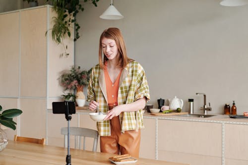 Woman in Yellow and Green Plaid Button Up Shirt and Brown Pants Standing Beside Brown Wooden