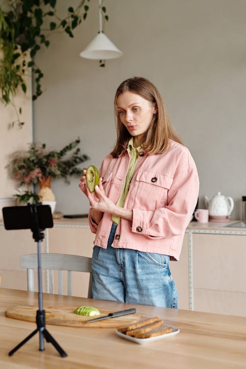 Woman in Pink Jacket Holding Sliced Avocado