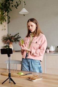 一名年轻女子在时尚的厨房里准备食物，拍摄视频博客