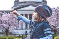 一个年轻女孩在历史建筑前指向樱花