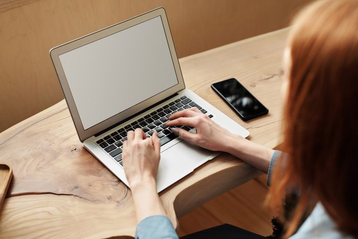 Someone typing on a laptop at a light wooden desk — photo by Mikael Blomkvist on Pexels