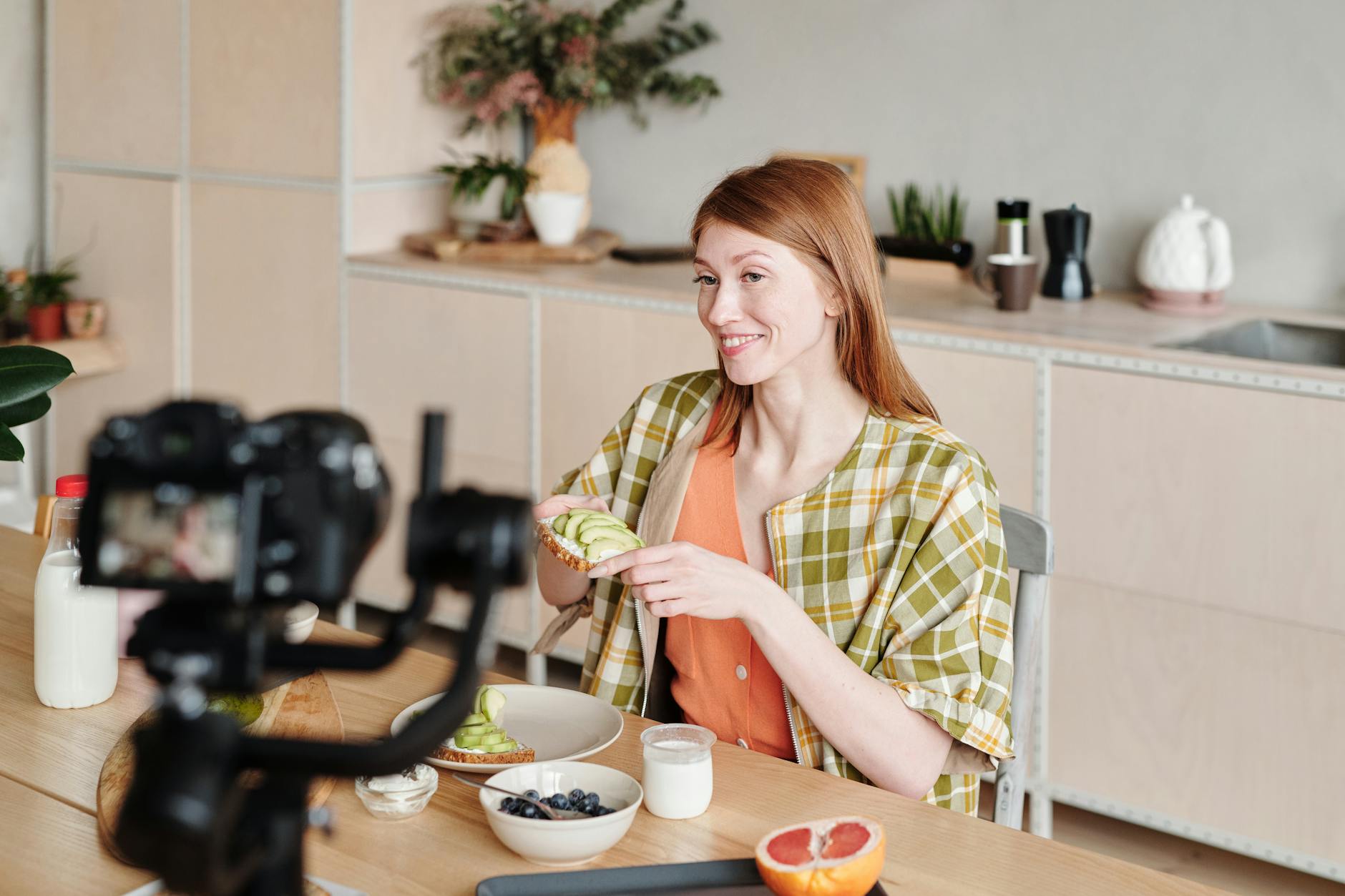 Smiling woman filming a vlog about making avocado toast at home