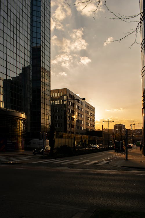 Scenery view of contemporary style multistage house exteriors on city street with asphalt road and marking lines under bright cloudy sky at sundown in evening