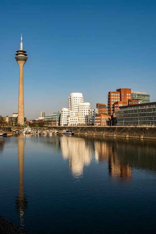 Contemporary house exteriors and high tower reflecting in river