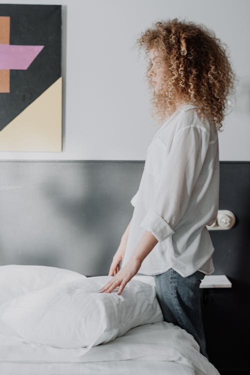 Free Woman in White Shirt and Blue Denim Jeans Sitting on White Wooden Table Stock Photo