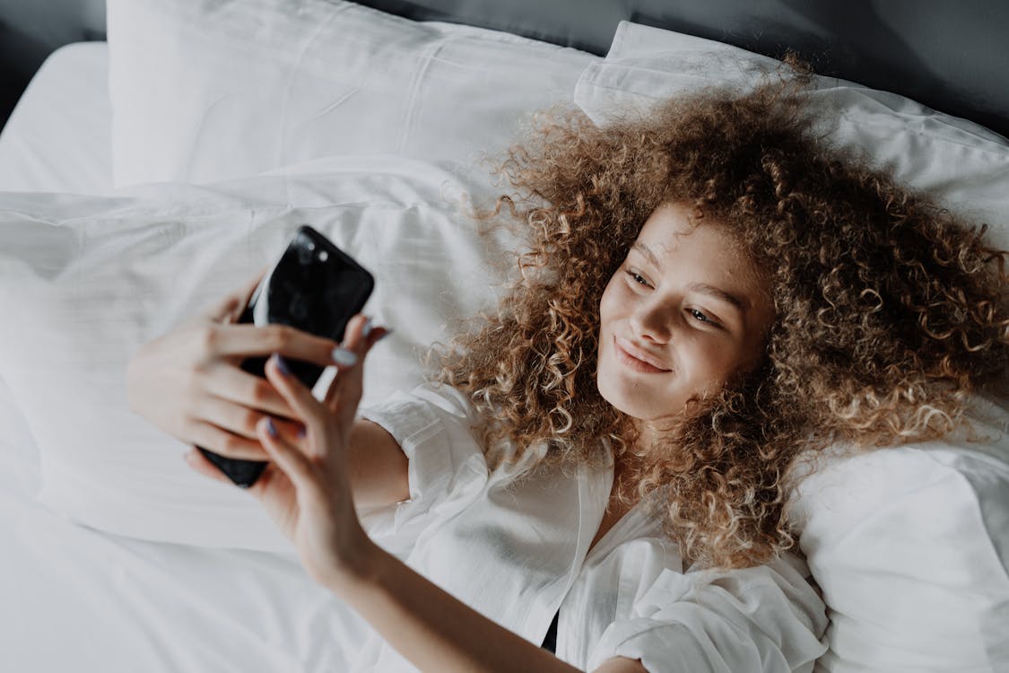 Free Woman in White Button Up Shirt Lying on Bed Stock Photo