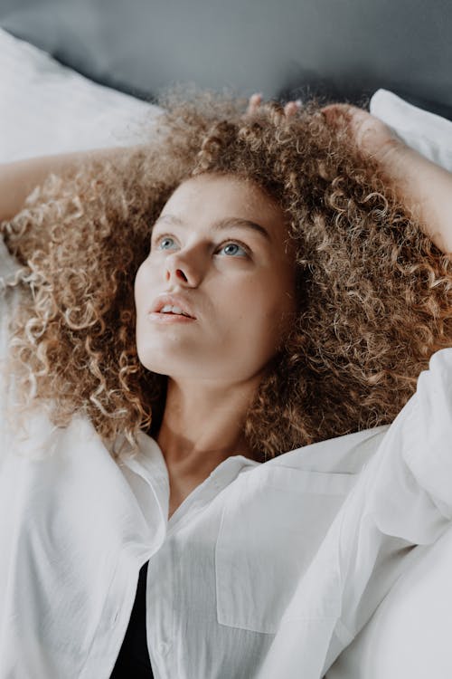 Free Woman in White Button Up Shirt Lying on Brown Textile Stock Photo