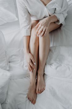 一位成年女性身披白色床单坐在床上，营造出轻松平静的氛围