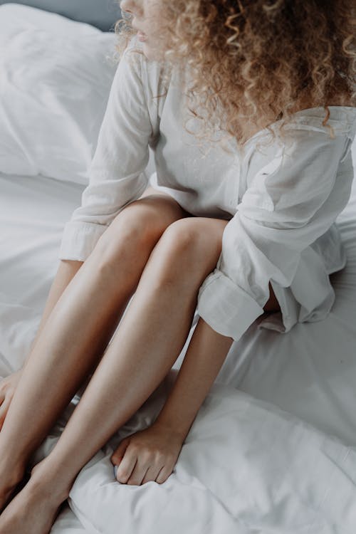 Free Woman in White Long Sleeve Dress Sitting on Bed Stock Photo