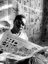 Grayscale Photo of Man Reading a Newspaper