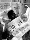 Person Wearing Metal Framed Eyeglasses Reading a Newspaper